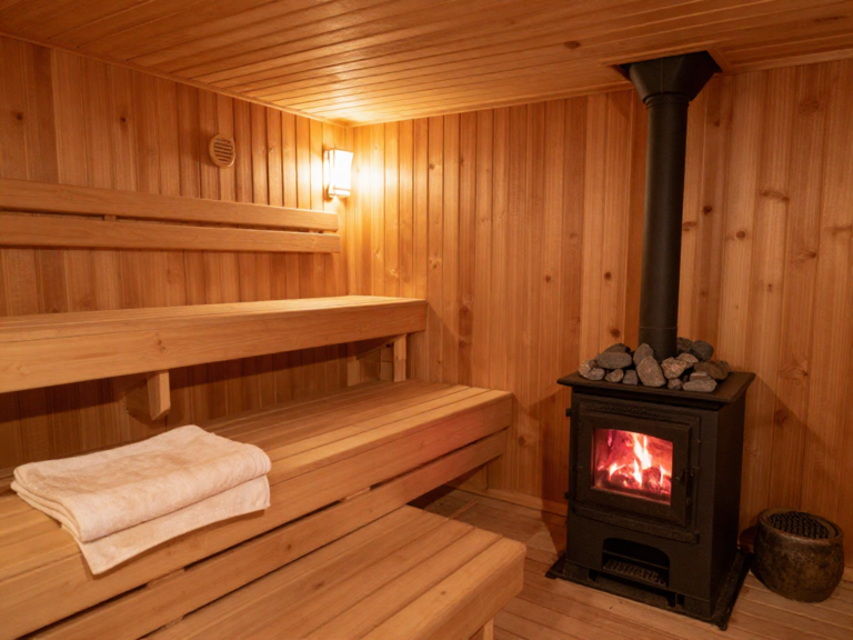 Traditional Finnish sauna interior with wooden bench, sauna stove, and proper towel placement